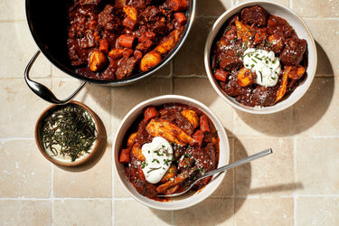 Rosemary Beef Stew in a bowl in front of a dutch oven