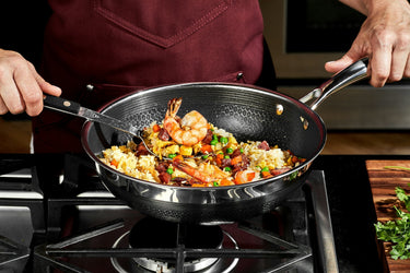 A person cooking shrimp fried rice in a HexClad wok.