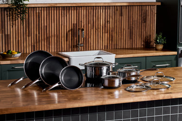 A HexClad cookware set sitting on a wooden countertop.