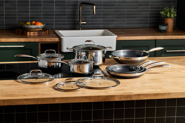 A HexClad pots and pans cookware set sitting atop a wooden countertop.