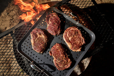 Four steaks cooking on the HexClad BBQ grill pan.