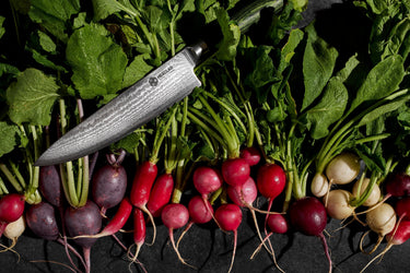 HexClad Chef Knife on top of a bed of Radishes