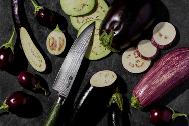 Different varieties of sliced, purple eggplant next to a HexClad chef