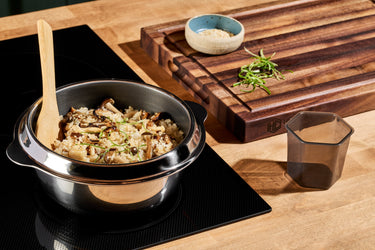 A dish of rice and mushrooms cooking on the stove in a HexClad Rice Pot.