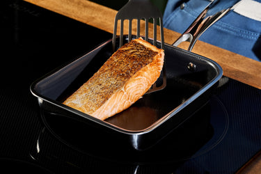 A piece of salmon being cooked in the HexClad Japanese square pan.