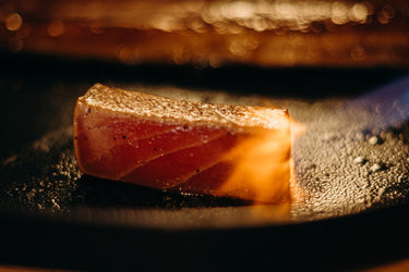 A tuna steak being seared in a pan.