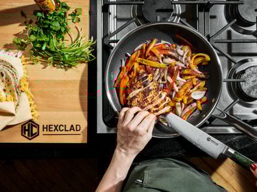 Someone cooking fajita vegetables & chicken in a HexClad pan, shown from a bird