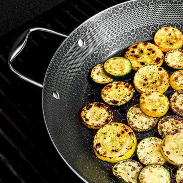 Pieces of squash and zucchini being cooked in the HexClad 12" Hybrid BBQ Grill Pan