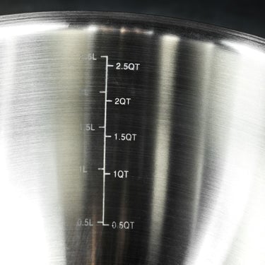 A closeup of the measurements on the side of a HexClad stainless steel mixing bowl.	