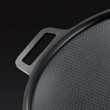 A closeup of the side handle of the HexClad hybrid pizza steel on a black background