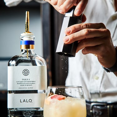 Hands grinding salt into a cocktail, using HexClad