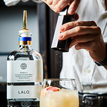 Hands grinding salt into a cocktail, using HexClad