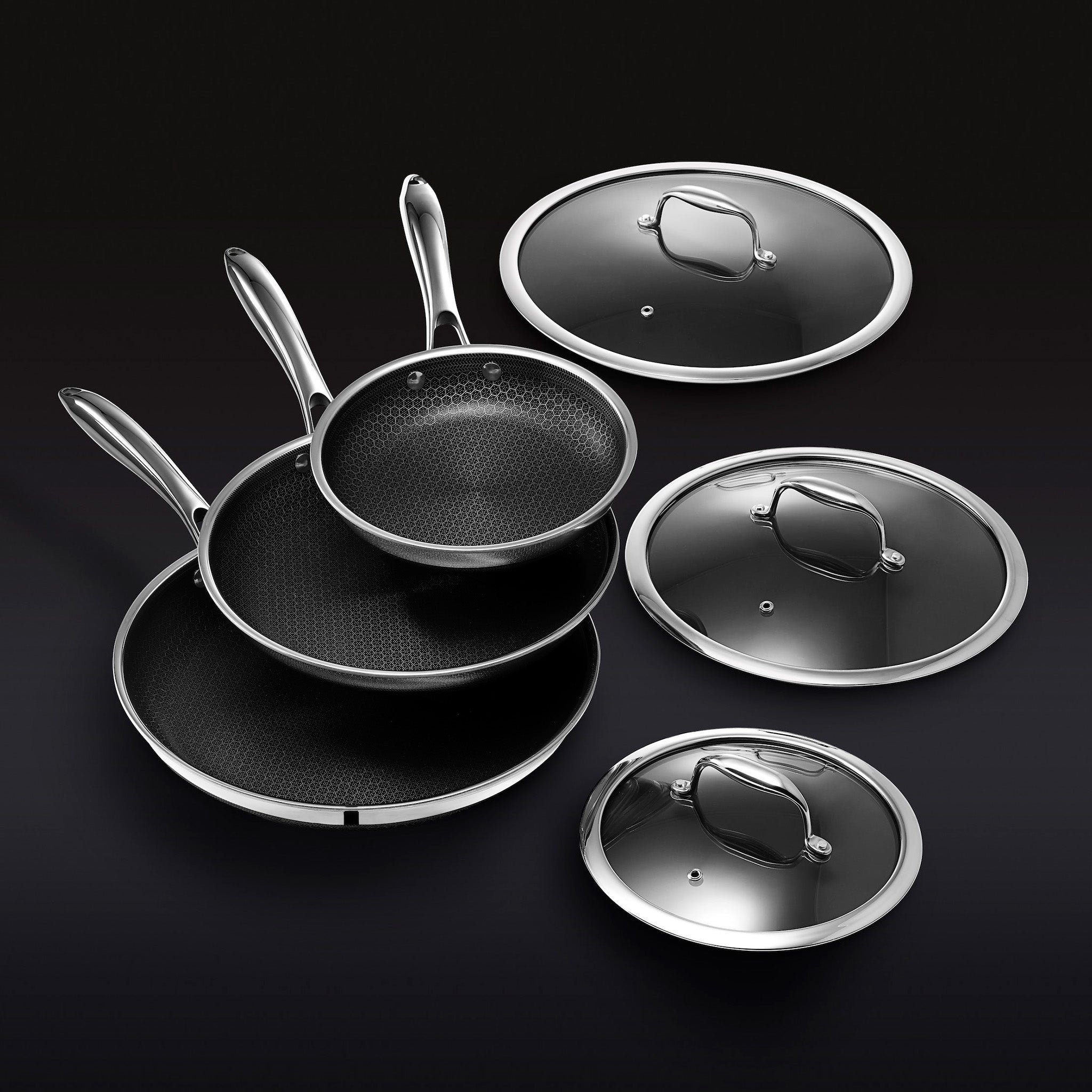 Three frying pans with lids on a black background.