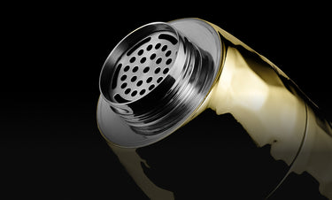 Shiny gold cocktil shaker with perforated top on a black background