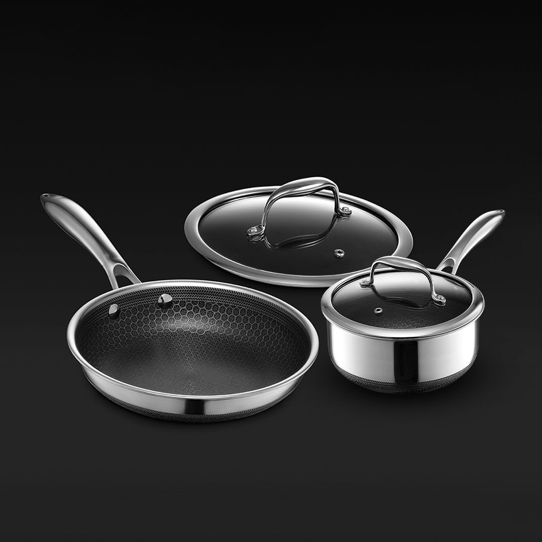 Three stainless steel cookware pieces with glass lids on a black background.
