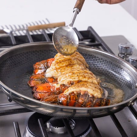 cooking lobster tails on a gas stove with a 12 inch frying pan