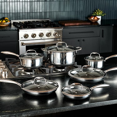 Stainless steel cookware set on a modern kitchen stove.