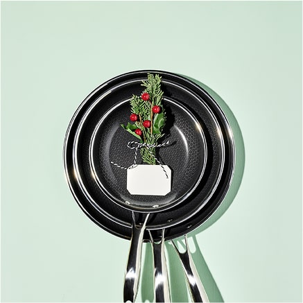 Stacked frying pans with a small festive decoration on top.
