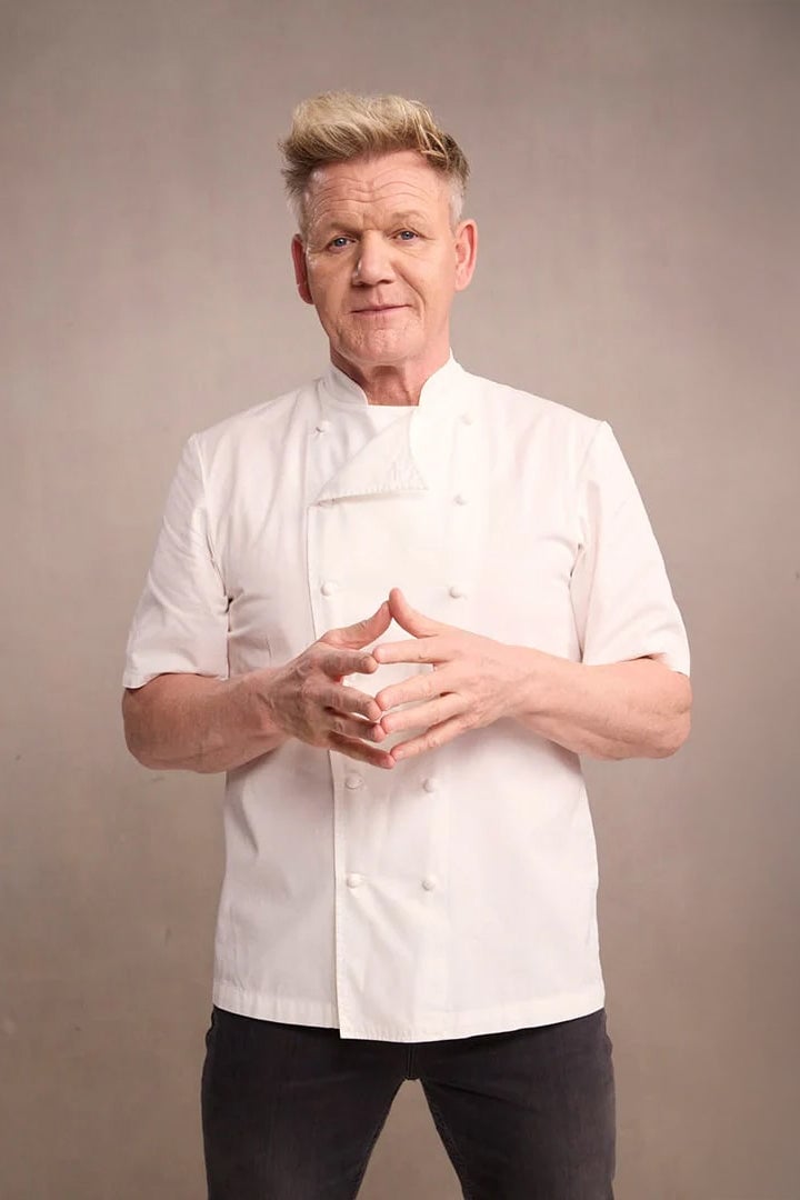 Chef smiling while cooking in a professional kitchen.
