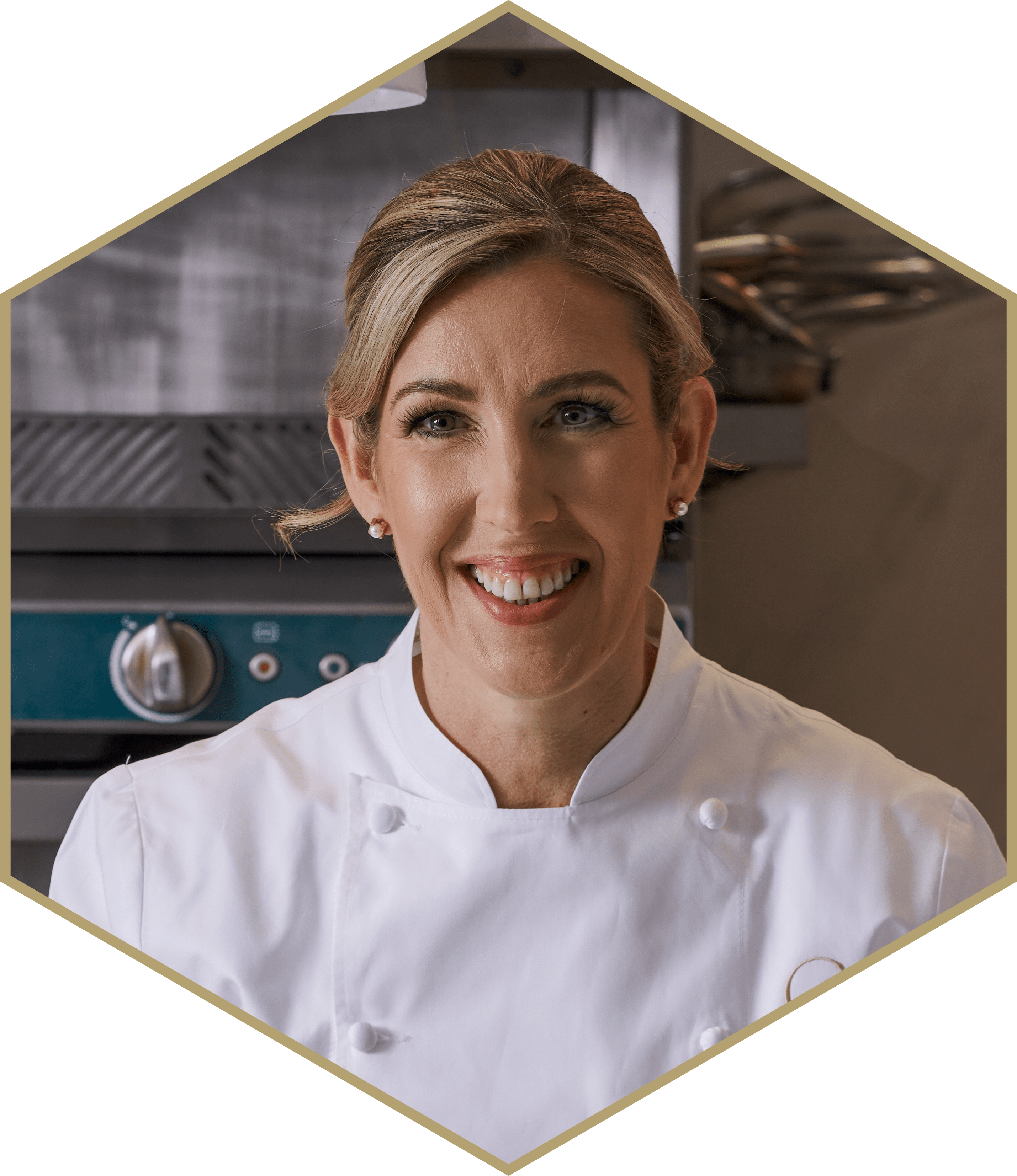 Chef smiling in a kitchen setting, wearing a white chef coat.