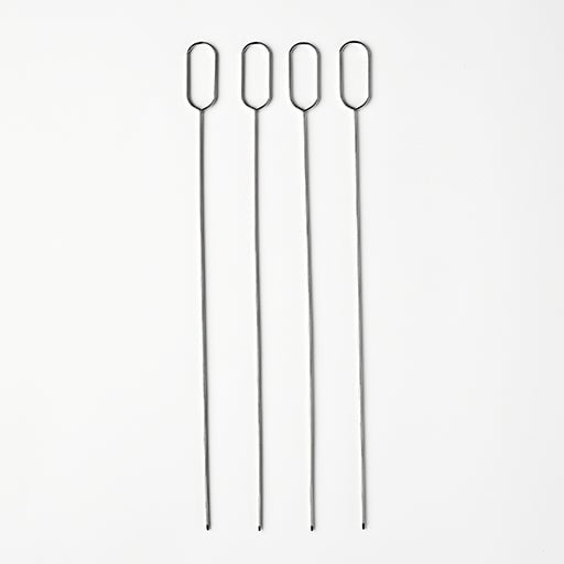 Four long metal skewers on a white background.
