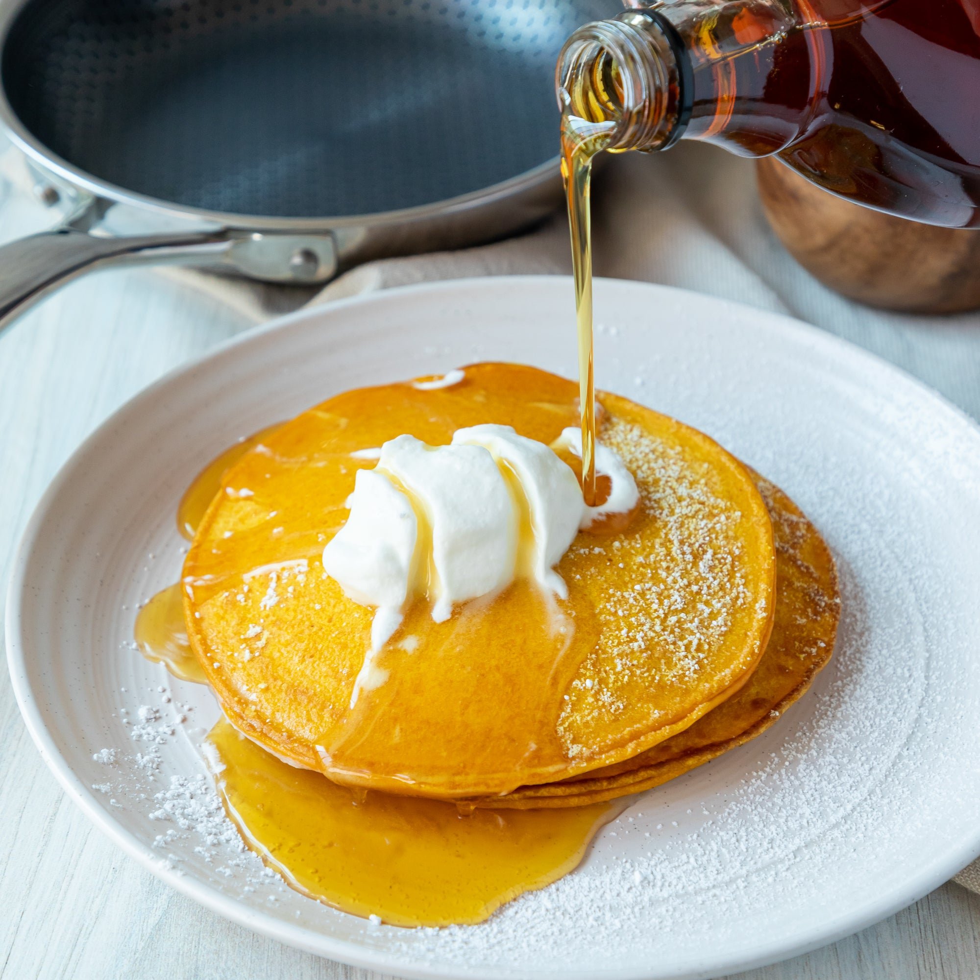 Pumpkin Pancakes With Whipped Cream and Maple Syrup in All Clad Pan