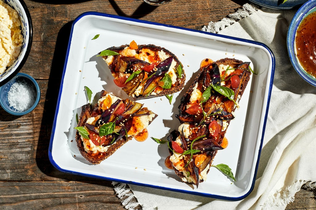 Sweet Chile & Ricotta Eggplant Toast on a white plate on a wooden table