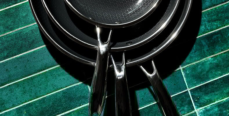 HexClad hybrid cookware featuring a stainless steel pan with a transparent glass lid. The pan's unique design ensures even heating and non-stick cooking for chef-quality results at home.