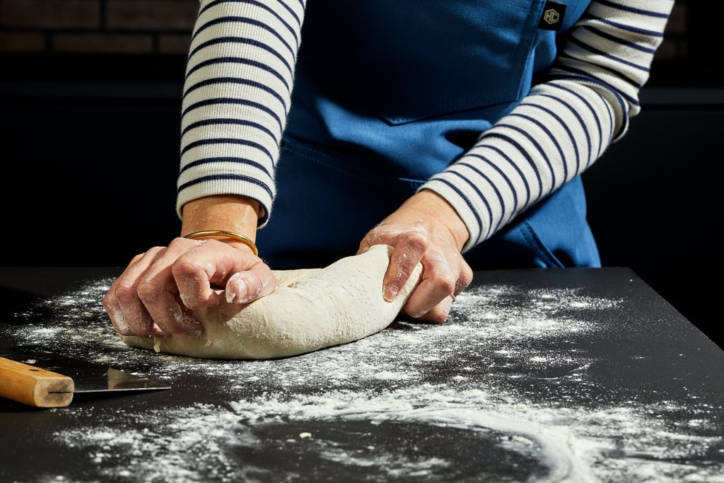 Hands stretching dough on black countertop