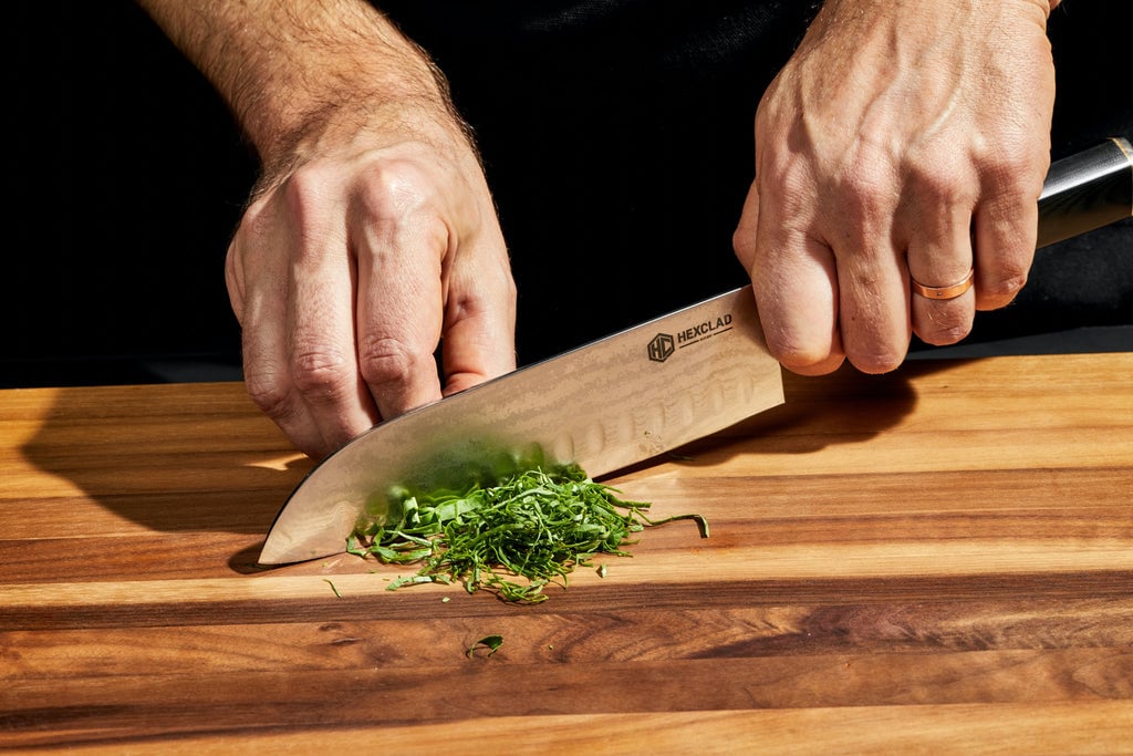 Hands using knife to cut leafy greens on cutting board