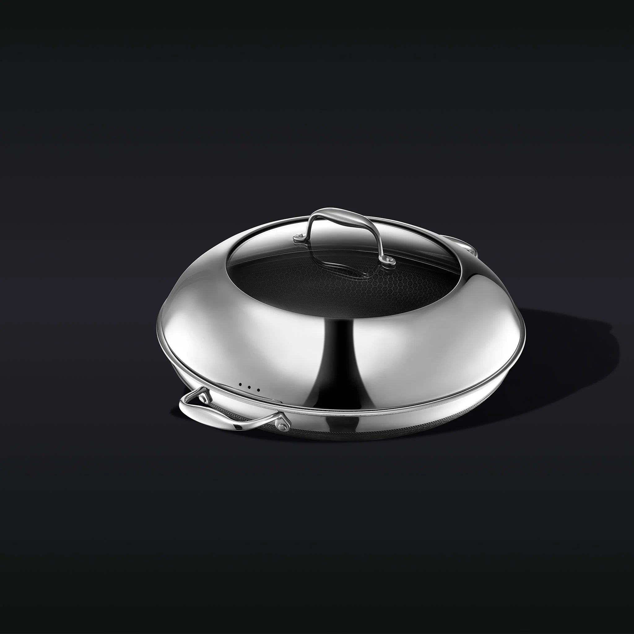 Stainless steel cooking pan with a lid on a dark background.