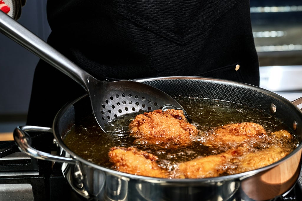 HexClad Wok Spoon scooping out chicken from hot oil