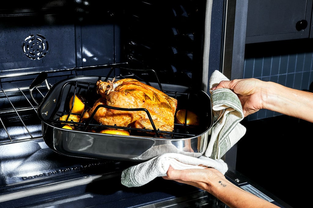 Chicken in a small roasting pan being put in the oven
