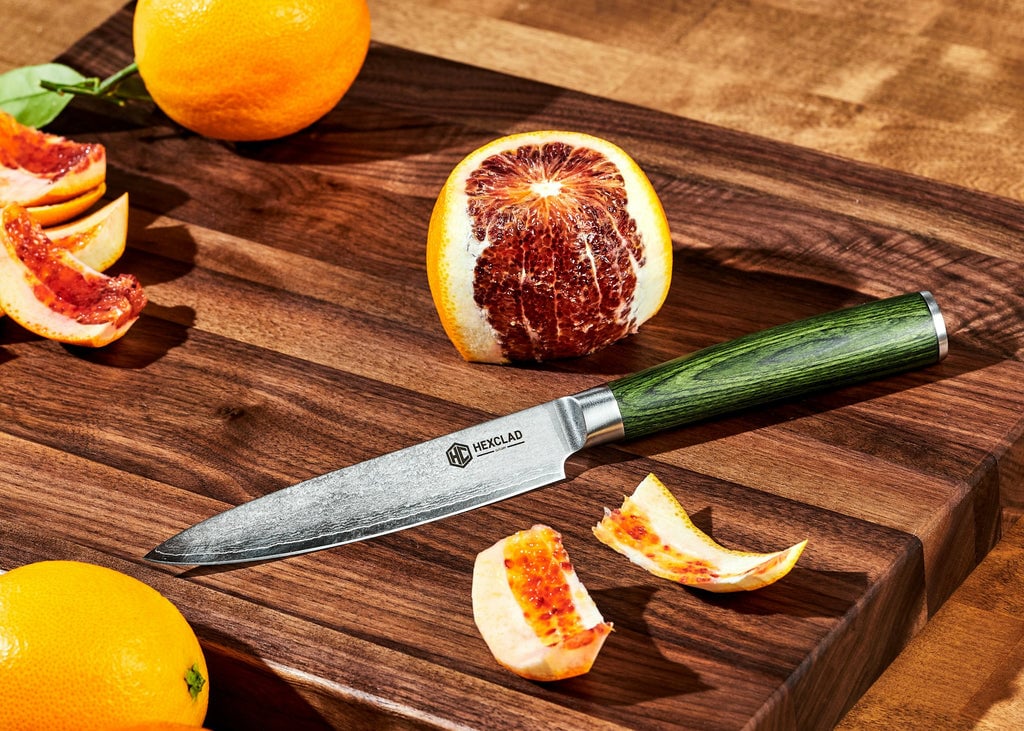 Paring knife on cutting board next to blood orange
