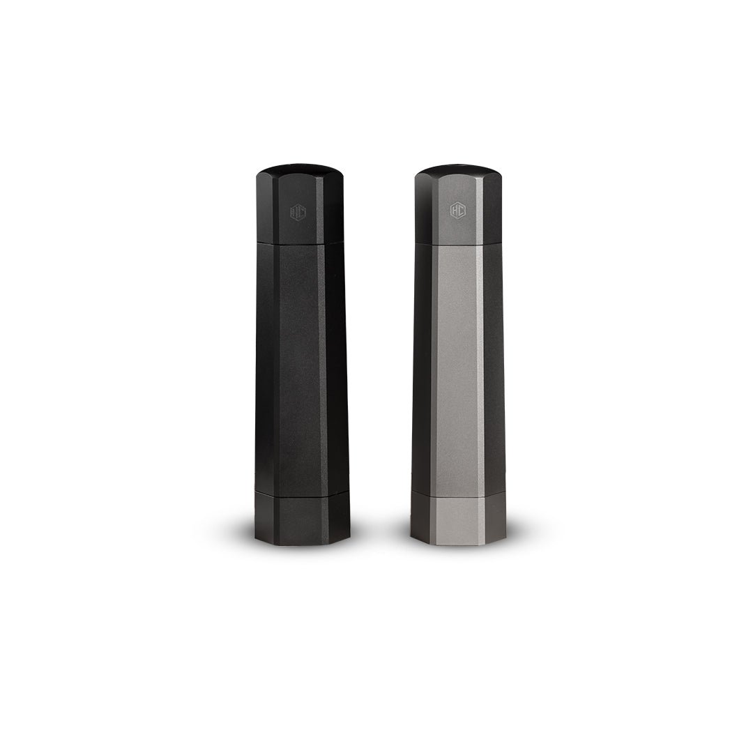 Two hexagonal pepper grinders in black and gray placed side by side.