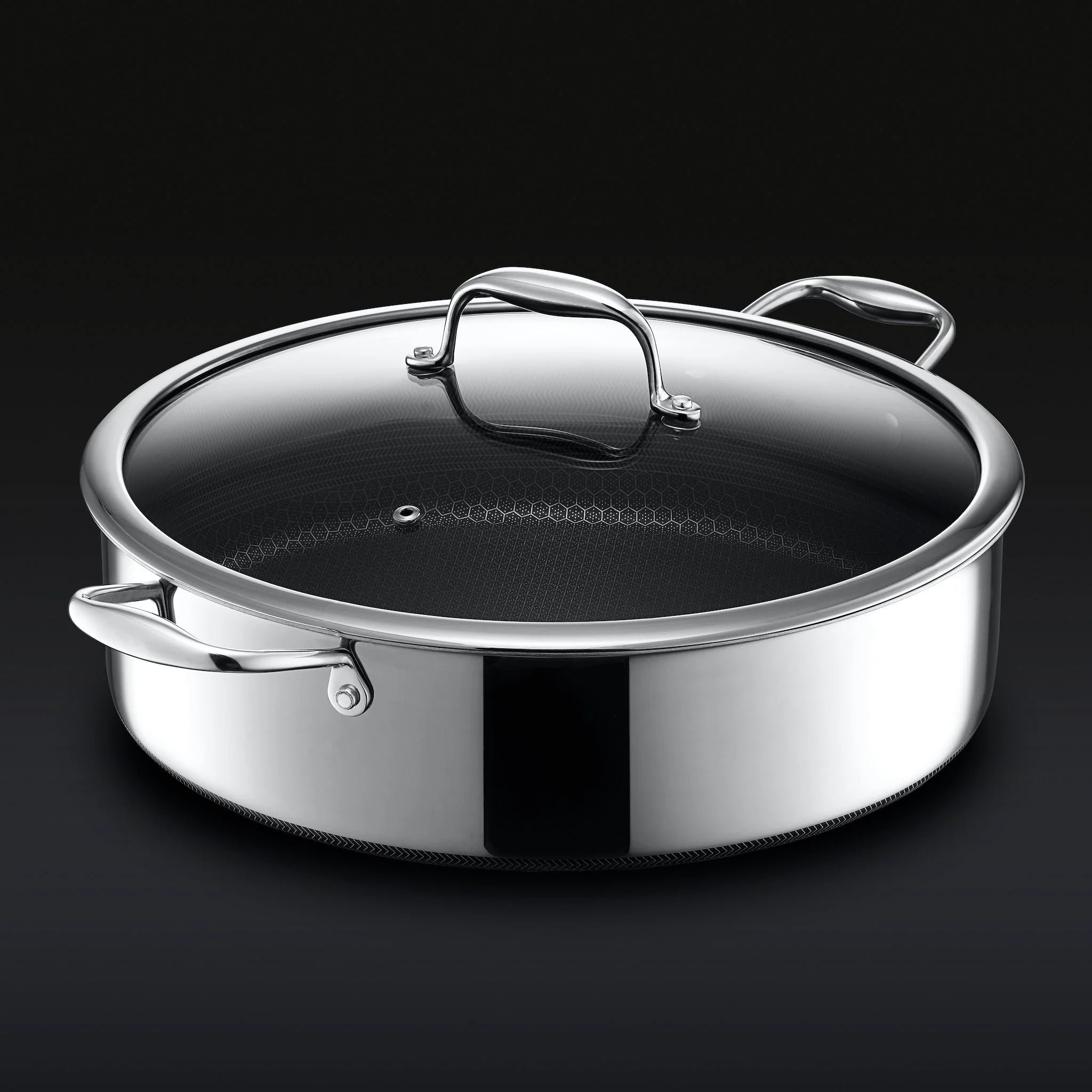 Stainless steel saute pan with glass lid and two handles on a dark background.