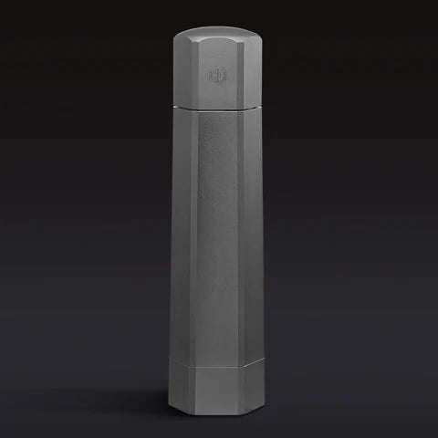 A tall, hexagonal, matte gray bottle against a dark background.