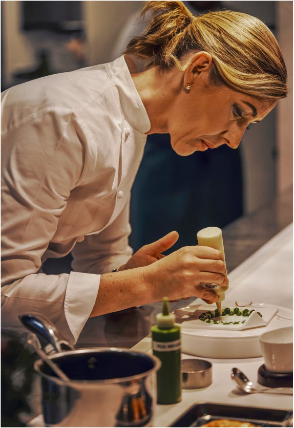 Chef expertly decorating a dish in a professional kitchen.
