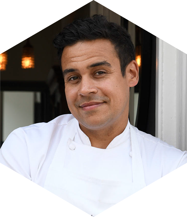 A chef in a white jacket smiling at the camera.