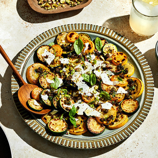 A plate of grilled zucchini salad garnished with basil and cheese.