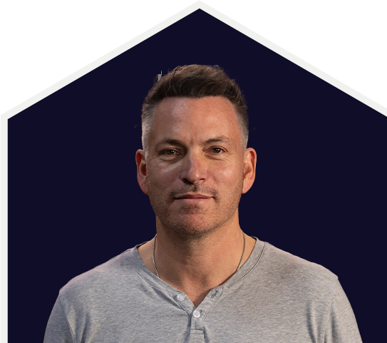 Man in a grey shirt against a dark background.