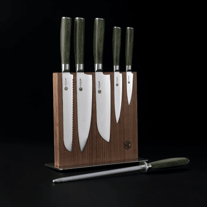 A set of four knives and a honing rod in a wooden knife block against a black background.