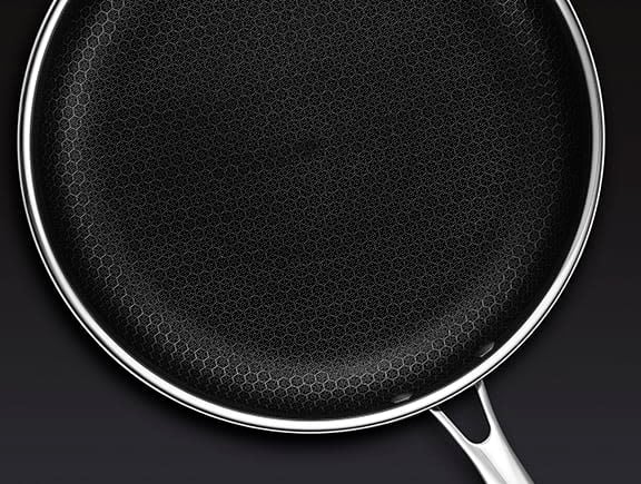 Non-stick frying pan with a honeycomb pattern on a black surface.