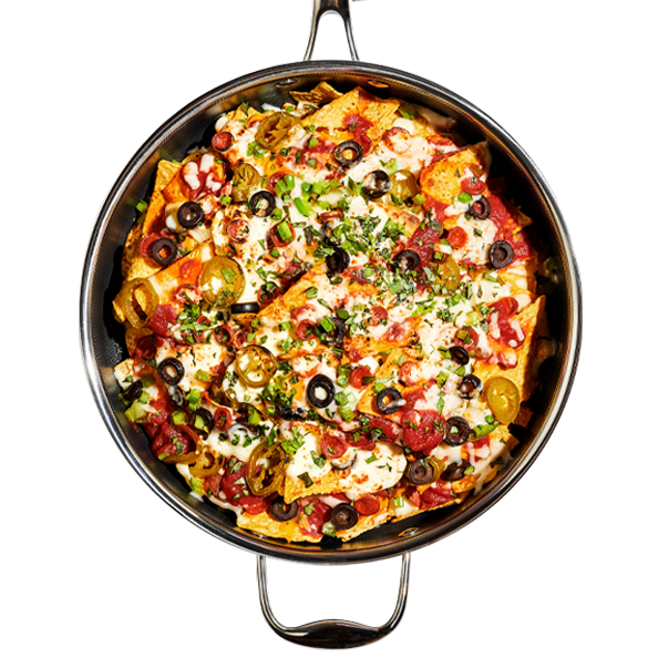 Pan of loaded nachos with olives, jalapeños, cheese, and herbs.