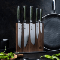 A set of kitchen knives in a wooden knife block next to a frying pan.